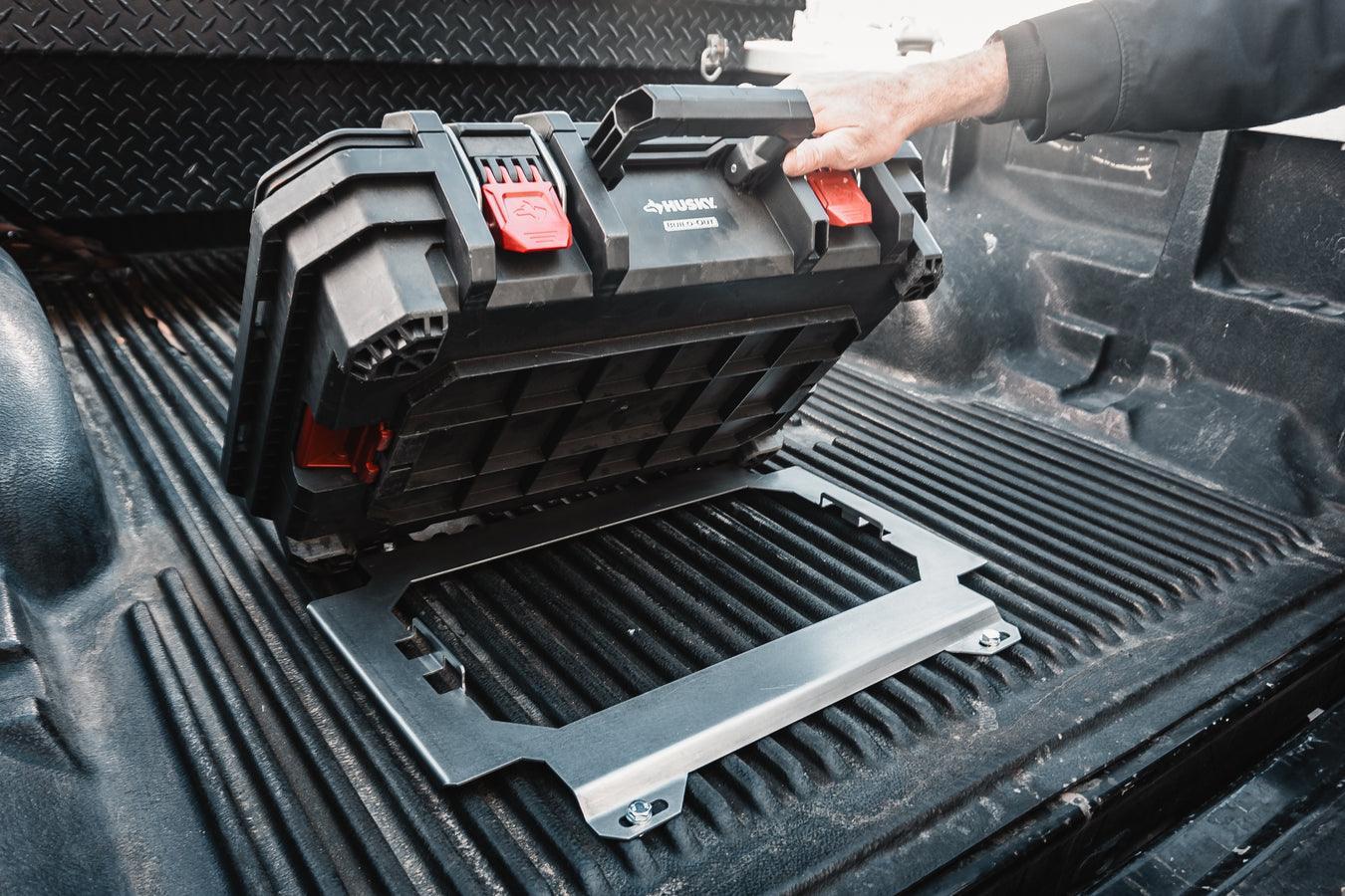 Husky Build-Out non-locking mounting plate installed on a truck bed liner, showing a secure, professional alternative to DIY toolbox lid mounts for mobile tool storage.