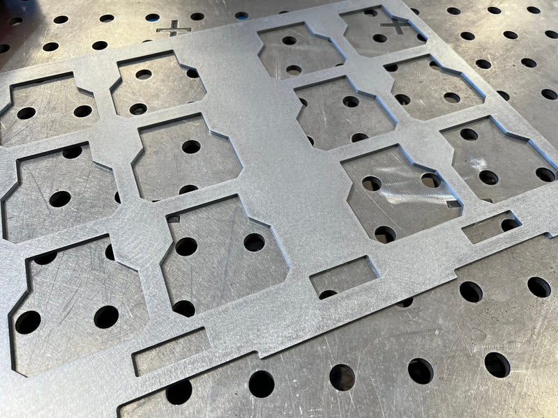 Metallic sheet with geometric cutouts and holes on a textured surface