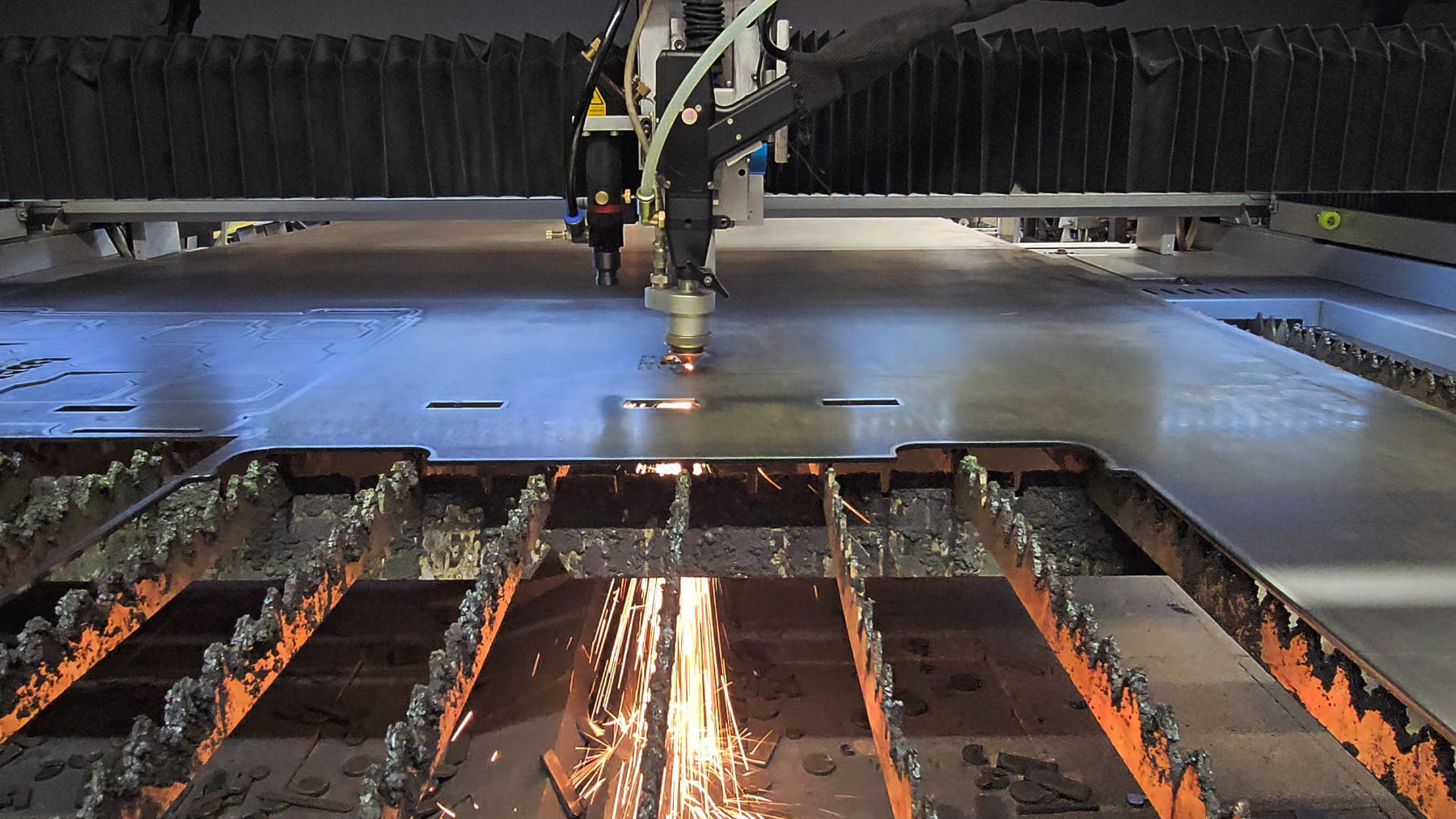 Industrial fiber laser cutting machine fabricating heavy-duty steel mounting plates at BOCO Custom LLC.