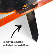 Close-up of the back of an orange steel pumpkin showing the removable black metal stake and mounting bracket for easy yard installation.