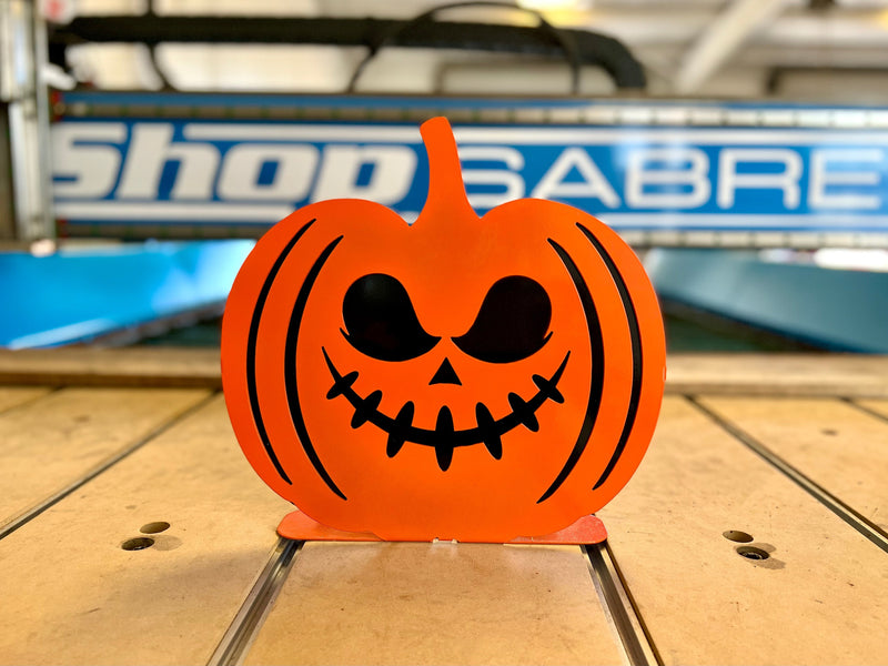 A 3D dual-layer steel pumpkin with a spooky face design, featuring large round eyes and a wide mouth with vertical "stitch" details.